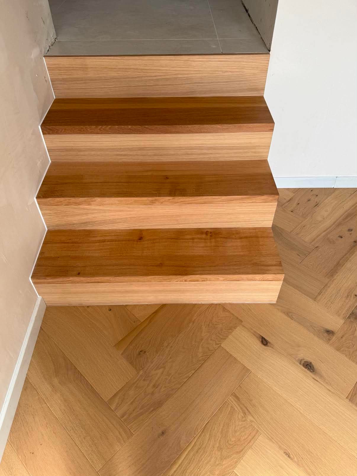 Premières marches d'un escalier en chêne massif posées au bord d'un parquet en point de Hongrie.