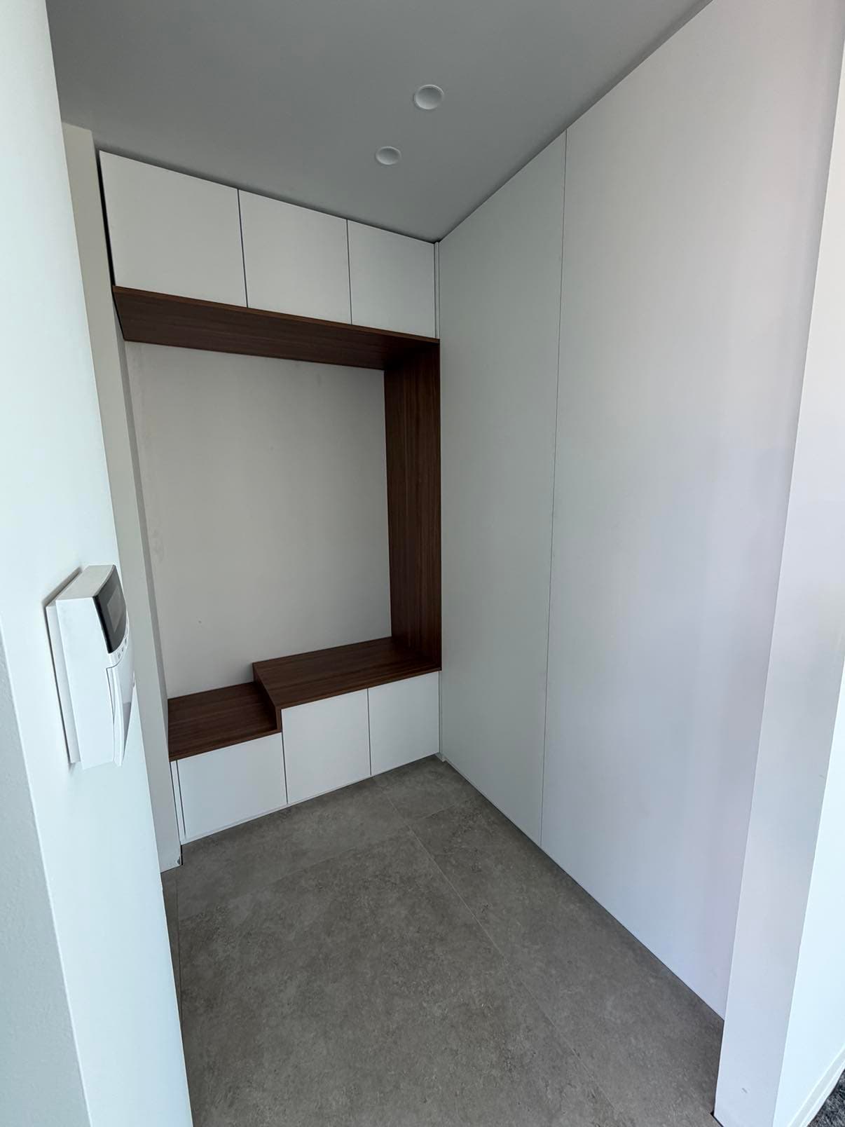 Hall d'entrée fermé par des placards blancs toute hauteur, avec une niche-banquette en noyer.